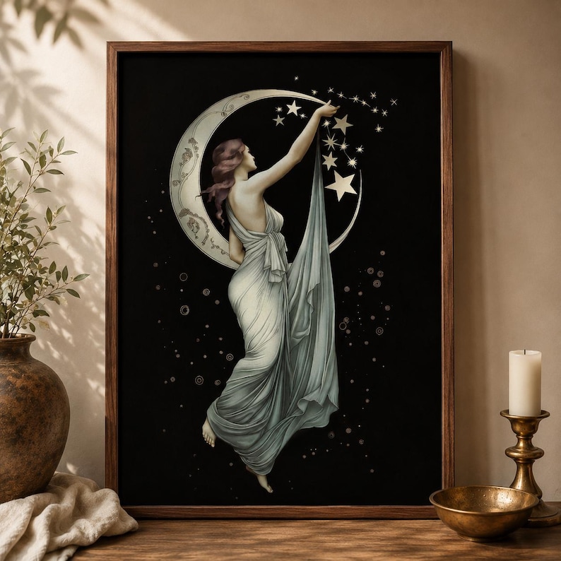May include: A framed wall art print featuring a figure in a flowing light-colored gown reaching toward a crescent moon and stars against a black background. The figure is positioned centrally, with the fabric of the gown draping downward.