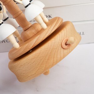Puede incluir: Una caja de m&uacute;sica de madera con un carrusel de figuritas de bailarinas. La caja est&aacute; hecha de madera clara y tiene una llave de cuerda en el lateral. Las bailarinas est&aacute;n pintadas de blanco y tienen el pelo negro.