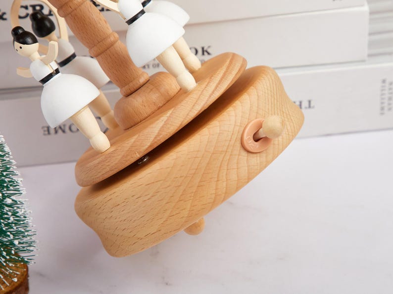 Puede incluir: Una caja de m&uacute;sica de madera con un carrusel de figuritas de bailarinas. La caja est&aacute; hecha de madera clara y tiene una llave de cuerda en el lateral. Las bailarinas est&aacute;n pintadas de blanco y tienen el pelo negro.