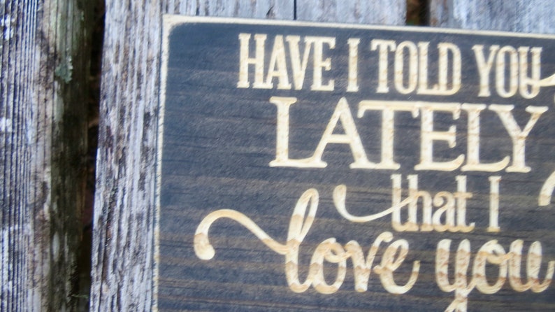 May include: A dark brown wooden sign with white lettering that reads "Have I told you lately that I love you".