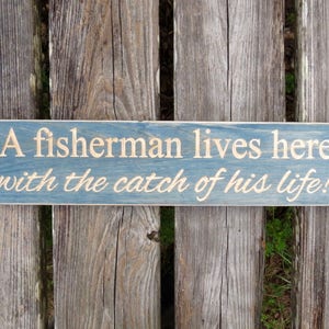 a fisherman lives here with the catch of his life sign, catch of his life, fisherman, fish, fisherman lives here, fishing sign, wood sign