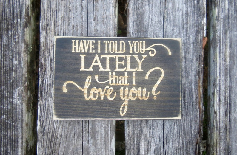 May include: A dark brown wooden sign with the text "Have I told you lately that I love you?" in gold lettering.