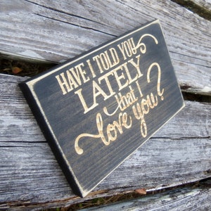 May include: Black wooden sign with gold lettering that reads "Have I told you lately that I love you?"