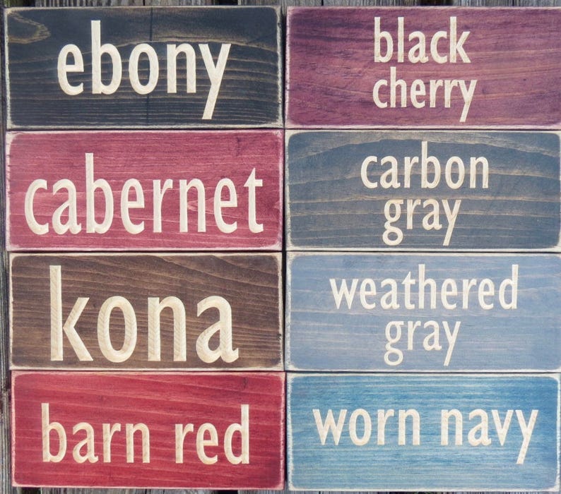 May include: Eight wooden signs with different wood stains and paint colors. The signs have the following text: ebony, cabernet, kona, barn red, black cherry, carbon gray, weathered gray, worn navy.