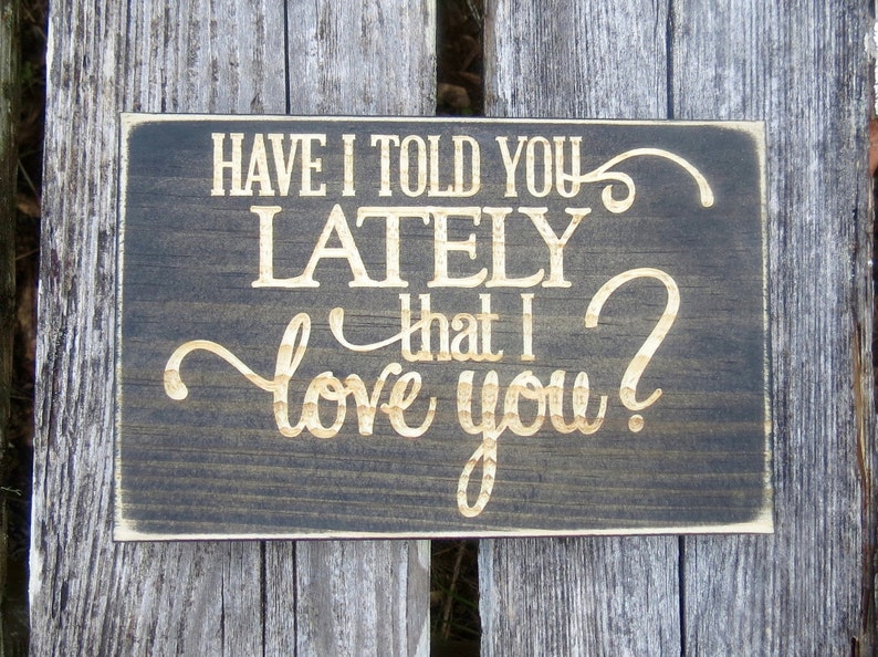 May include: A dark brown wooden sign with the text "Have I told you lately that I love you?" in gold lettering.