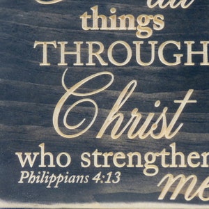 May include: A black wooden sign with white text that reads "I can do all things through Christ who strengthens me. Philippians 4:13".