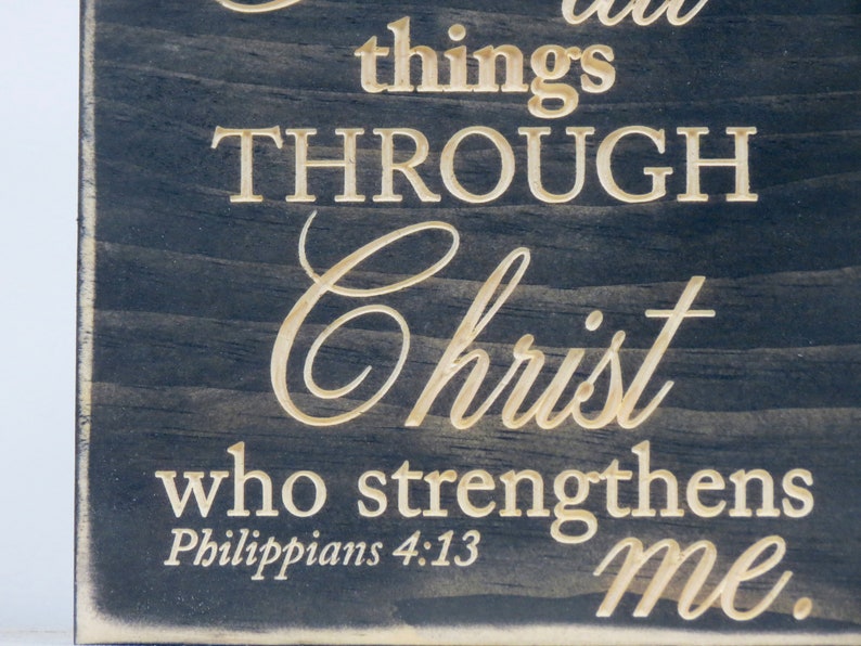 May include: A black wooden sign with white text that reads "I can do all things through Christ who strengthens me. Philippians 4:13".