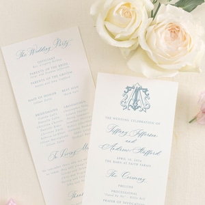 May include: Elegant wedding ceremony programs with light blue text, featuring the names of the couple, Tiffany Jefferson and Andrew Stafford, and the wedding party details. White roses and purple flowers accent the stationery.