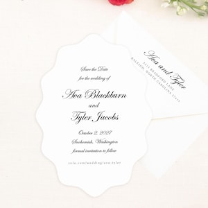 May include: A white wedding invitation with a scalloped edge, featuring the names Ava Blackburn and Tyler Jacobs, and the date October 2, 2027. The invitation is accompanied by a white envelope and surrounded by red and peach roses and white flowers.