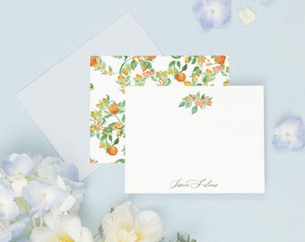 May include: A white card with a floral pattern of orange blossoms and green leaves. The card is folded in half and has the text "invited by LAMAWORKS" printed on the bottom right corner. The card is on a light blue background with white and blue flowers.