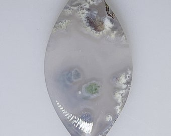 May include: A white agate cabochon with green and grey inclusions. The cabochon is shaped like a teardrop and has a smooth, polished surface.