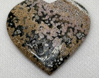 May include: A heart-shaped piece of ocean jasper with a brown, black, and white speckled pattern.