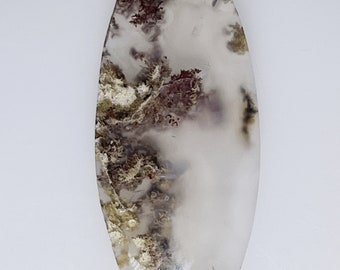 May include: A white agate cabochon with brown and red dendritic inclusions. The cabochon is oval shaped and has a smooth, polished surface.