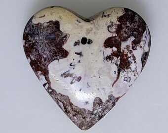 May include: A heart-shaped stone pendant with a white and brown marbled pattern. The stone has a hole drilled through the top for hanging.