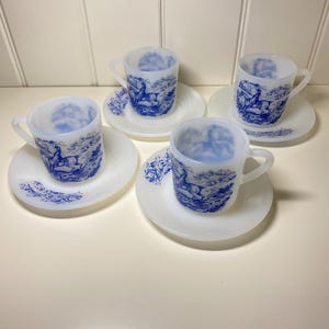 Può includere: Quattro tazze e piattini vintage bianchi e blu. Le tazze e i piattini sono bianchi con un disegno paesaggistico blu con un cervo. Le tazze hanno manici e sono su piattini abbinati.