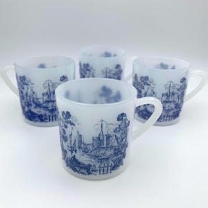 May include: Set of four white ceramic mugs with blue and white landscape designs. The mugs have a frosted finish and a simple handle.