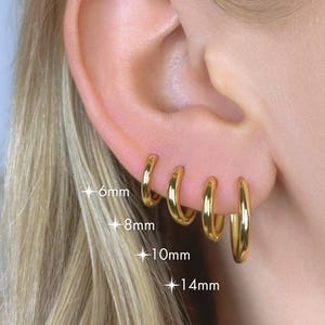 May include: A white ceramic mug with a black handle and the text "But First, Coffee" in a black, handwritten-style font. The mug is on a white surface.