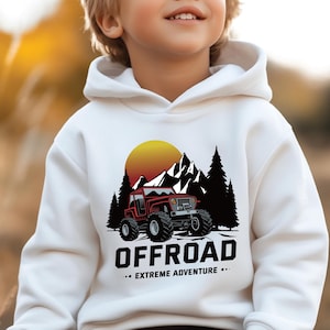 Puede incluir: Sudadera con capucha blanca con un jeep rojo conduciendo por un paisaje montañoso con una puesta de sol en el fondo. El texto "OFFROAD... EXTREME ADVENTURE..." está impreso debajo del jeep.