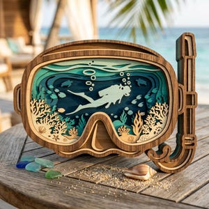 Puede incluir: Una pieza de arte mural de madera multicapa con forma de máscara de buceo y tubo. El interior presenta una escena submarina cortada con láser con un buceador, arrecifes de coral, tortugas marinas y peces en tonos azules, turquesas y madera.