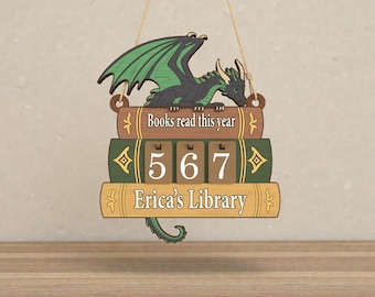 May include: Wooden dragon-themed book counter with the text "Books read this year" and "Erica's Library". The counter displays the number 567. The dragon is black with green wings.