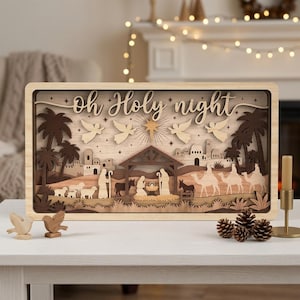 May include: A rectangular wooden layered nativity scene featuring the text Oh Holy Night, depicting a manger, figures, camels, sheep, palm trees, and angels under a star. The scene is crafted from various shades of light and dark wood.