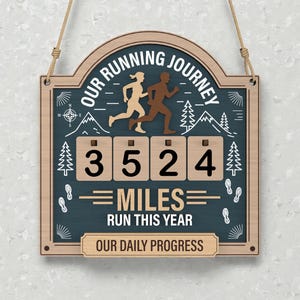 以下が含まれることがあります： 「OUR RUNNING JOURNEY」と「3524 MILES RUN THIS YEAR」の文字が入った木製サイン。ランニングする人物、木、山、足跡が描かれています。下部には「OUR DAILY PROGRESS」と書かれています。