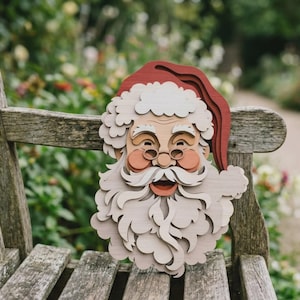 May include: A layered wooden wall decoration shaped like a Santa Claus face. The piece features a red hat, a thick white beard, a moustache, round glasses, and rosy cheeks, constructed from multiple stacked wood cutouts to create a 3D effect.