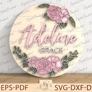 May include: A round wooden sign with a pink floral design and the name "Adeline Grace" written in pink script.