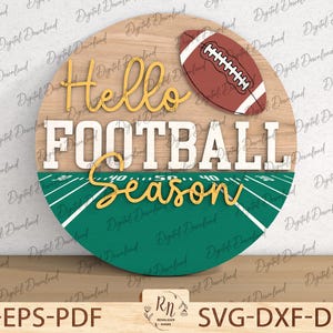 Könnte beinhalten: Runder Holzschild mit den Worten "Hello FOOTBALL Season" in weißer und goldener Schrift. Es zeigt einen braunen Football und ein grünes Footballfeld-Design. Es ist ein digitaler Download.