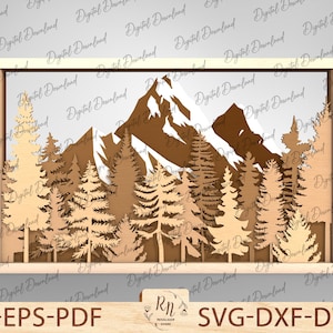 May include: A laser cut design of a mountain scene with a forest of trees in front of the mountain. The design is framed in a square frame.