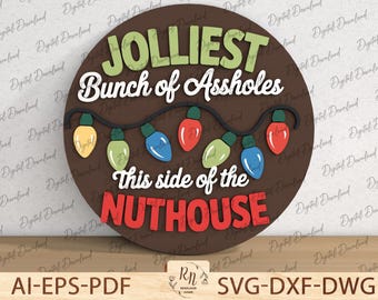 May include: A round, brown sign with the text "JOLLIEST Bunch of Assholes" in white and green. Below, it reads "This side of the NUTHOUSE" in red. A string of colorful Christmas lights decorates the sign. The sign is a digital download.