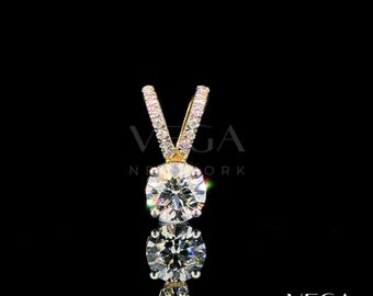 May include: A diamond pendant featuring a large, round-cut central stone. The pendant is set in a gold setting with a V-shaped bail, adorned with smaller diamonds. The background is black, with the text "VEGA NEW YORK".