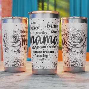 Könnte beinhalten: Drei Edelstahlbecher mit weißem Hintergrund und schwarzen Blumenmustern. Der mittlere Becher hat den Text "kind admired worthy brave sweet mama rare you are fun needed precious amazing bright" aufgedruckt.