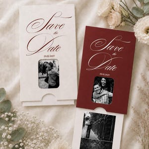 Puede incluir: Dos tarjetas rectangulares Save the Date con insertos deslizantes. Una tarjeta es color crema con texto rojo oscuro, la otra es rojo oscuro con texto blanco. Ambas presentan el texto Save the Date, la fecha 29.01.2027 y un recorte cuadrado.