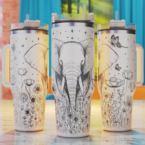 May include: Three white stainless steel tumblers with a black and white design of an elephant and flowers. The tumblers have lids and straws.
