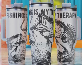 May include: White stainless steel travel mug with a black and white illustration of a fish jumping out of the water. The mug has a handle and a lid with a straw. The text "Fishing is my therapy" is printed on the mug.