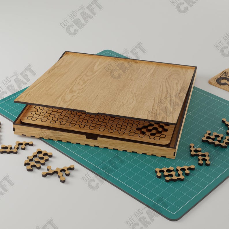 May include: A wooden puzzle box with a lid that opens to reveal a complex maze pattern. The puzzle pieces are scattered on a green mat.
