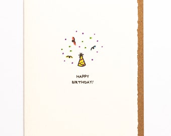 May include: A white card with a hand-drawn illustration of a party hat with confetti and the text "Happy Birthday!"