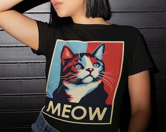 May include: Black t-shirt with a graphic of a cat in a red, white, and blue color scheme. The cat is looking up with its mouth closed. The text "MEOW" is below the cat.
