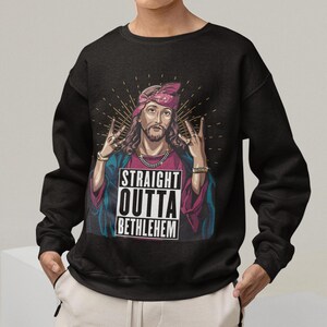 May include: Black sweatshirt with a graphic of Jesus wearing a bandana and making a hand gesture. The graphic also includes the text "Straight Outta Bethlehem".