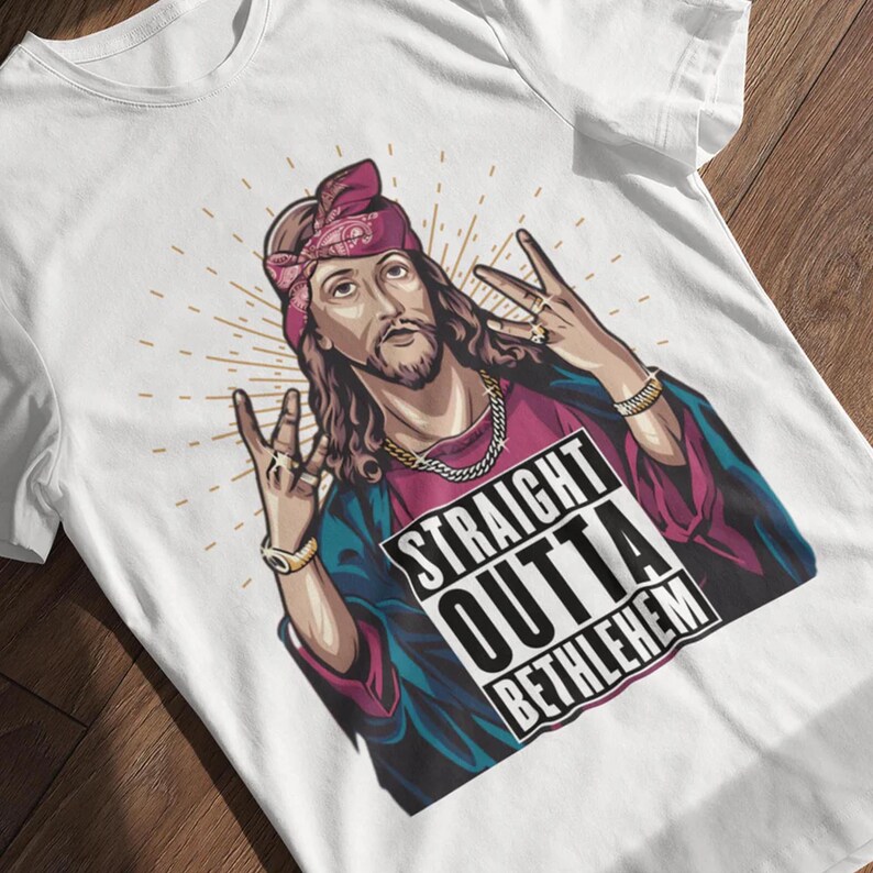May include: White t-shirt with a graphic of Jesus wearing a bandana and a gold chain. The graphic says "Straight Outta Bethlehem".