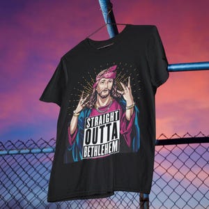 May include: Black t-shirt with a graphic of Jesus wearing a bandana and a gold chain. The graphic says "Straight Outta Bethlehem".