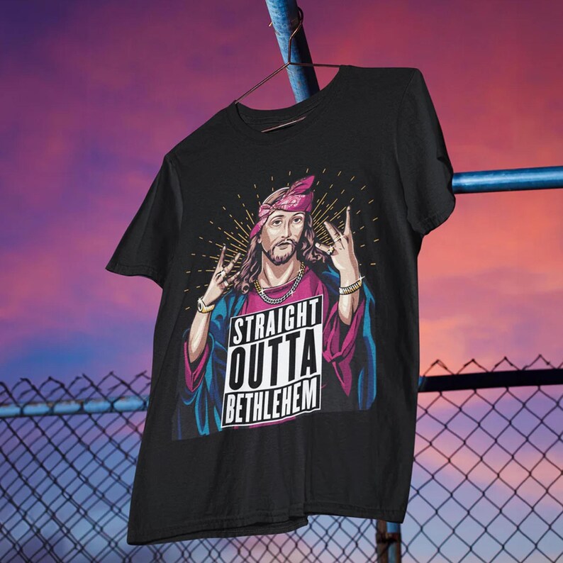 May include: Black t-shirt with a graphic of Jesus wearing a bandana and a gold chain. The graphic says "Straight Outta Bethlehem".