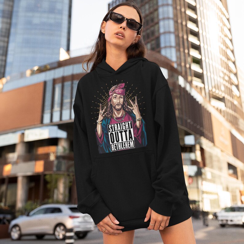 May include: Black hoodie with a graphic of Jesus wearing a bandana and making a rock and roll hand gesture. The graphic says "Straight Outta Bethlehem".