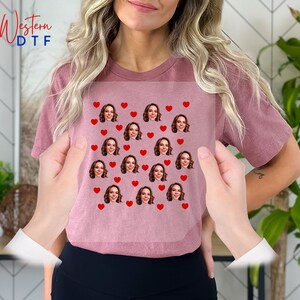 a woman holding up a t - shirt with hearts on it