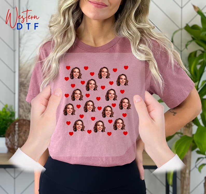 a woman holding up a t - shirt with hearts on it