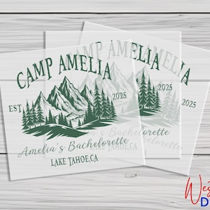 May include: A white background with a green and black design of mountains, trees, and the text "Camp Amelia Est. 2025 Amelia's Bachelorette Lake Tahoe, CA"