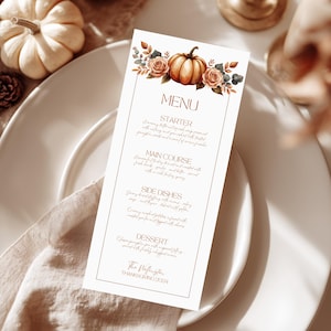 May include: A Thanksgiving menu card with a watercolour pumpkin and floral design. The menu is printed on a cream-coloured card and is displayed on a white plate with a linen napkin. The menu includes the text "MENU", "STARTER", "MAIN COURSE", "SIDE DISHES", and "DESSERT".