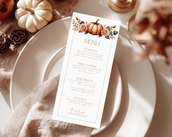 Könnte beinhalten: Eine Thanksgiving-Menükarte mit einem Aquarell-Kürbis- und Blumendesign. Das Menü ist auf einer cremefarbenen Karte gedruckt und wird auf einem weißen Teller mit einer Leinen-Serviette präsentiert. Das Menü enthält den Text "MENU", "STARTER", "MAIN COURSE", "SIDE DISHES" und "DESSERT".