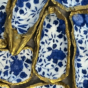 May include: A collection of decorative oyster shells with a blue and white floral pattern and gold accents.